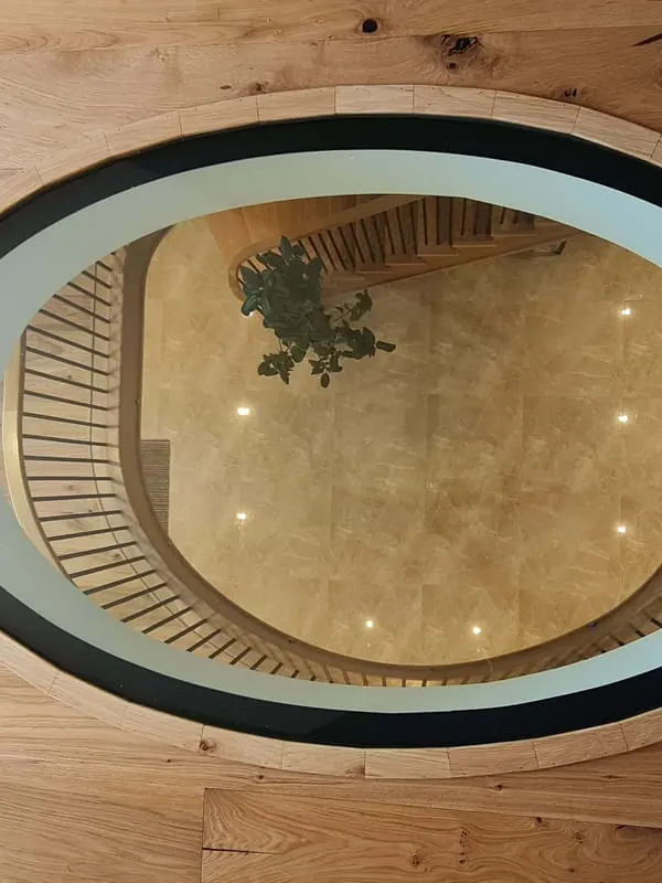Round glass floor panel set into an oak floor above a staircase