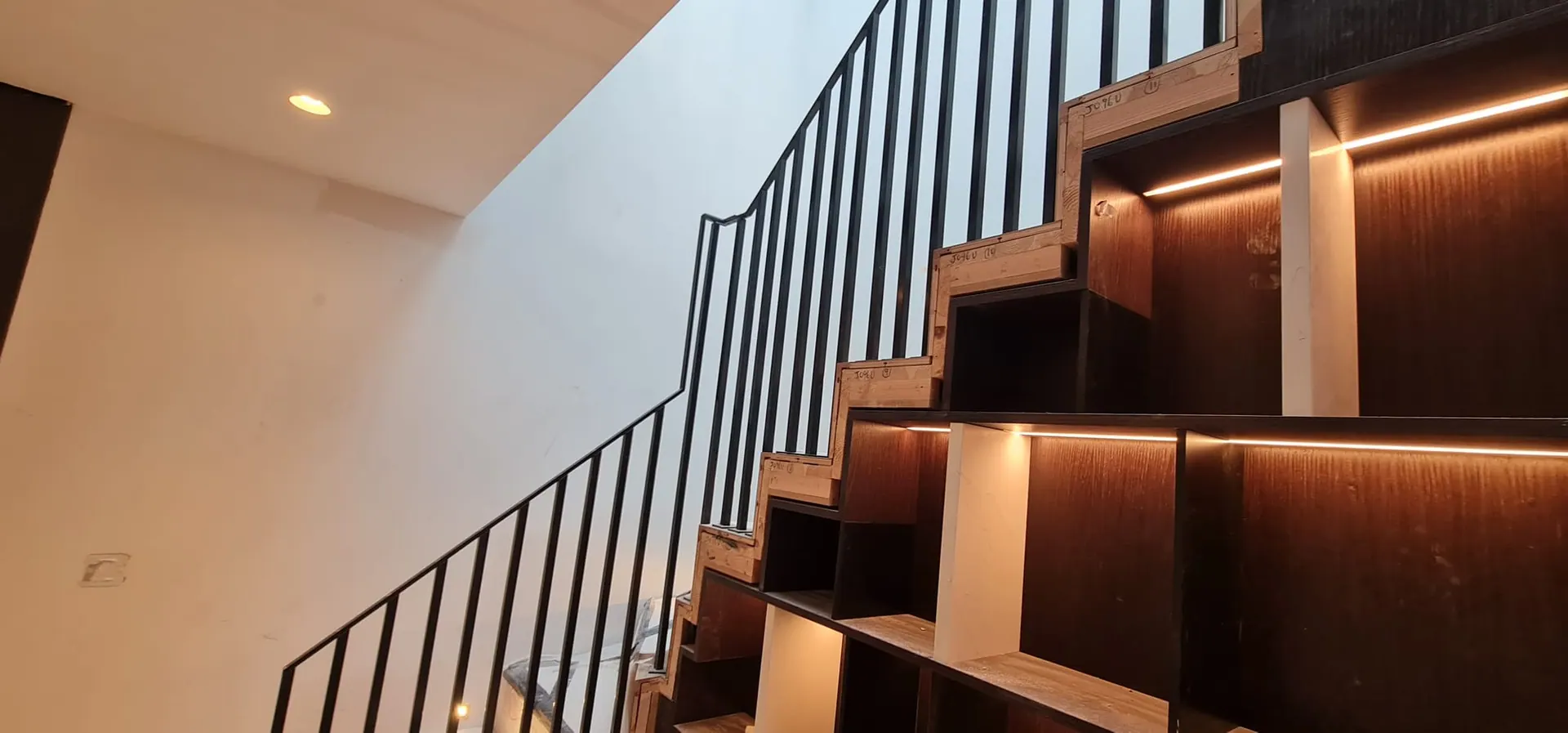 Staircase with built-in lit bookshelves beneath the treads