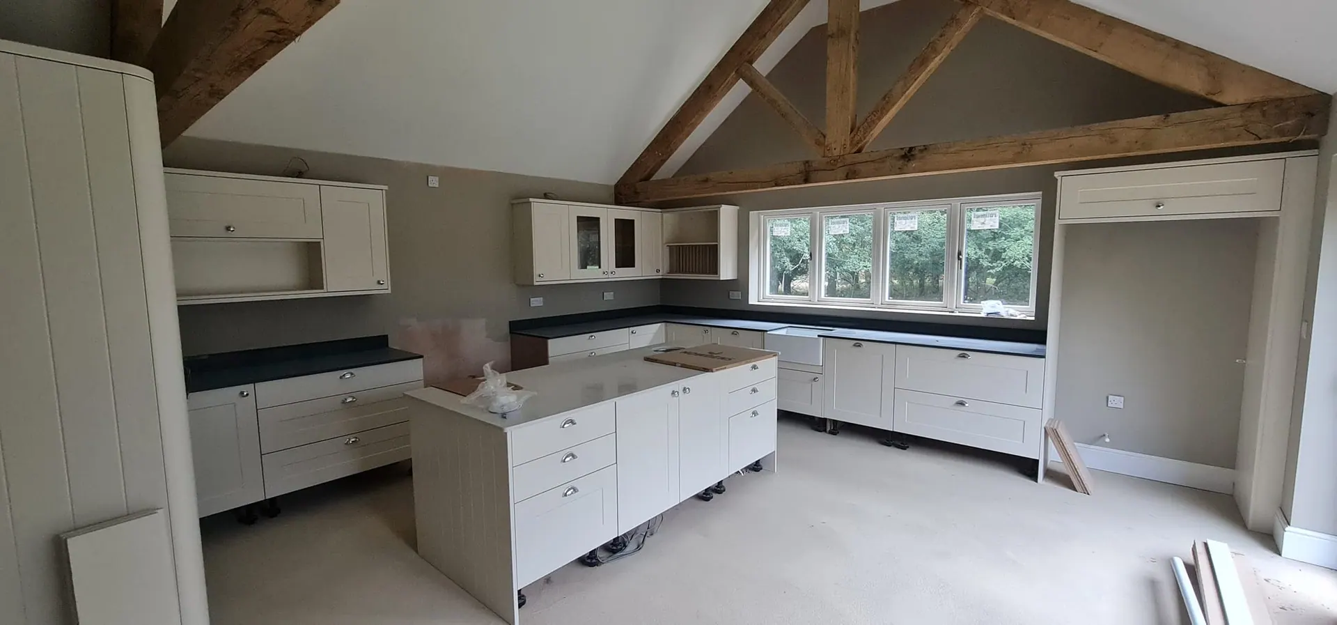 Painted kitchen with an island under exposed oak roof trusses