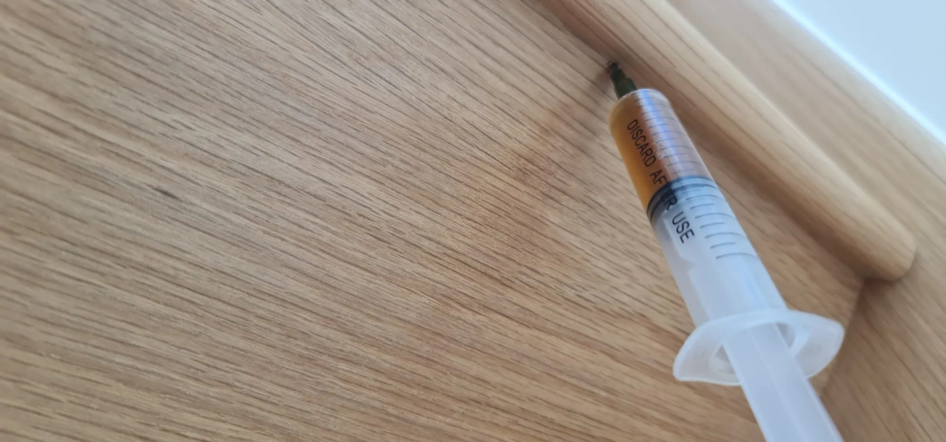 Adhesive being injected under an oak stair tread to stop it moving