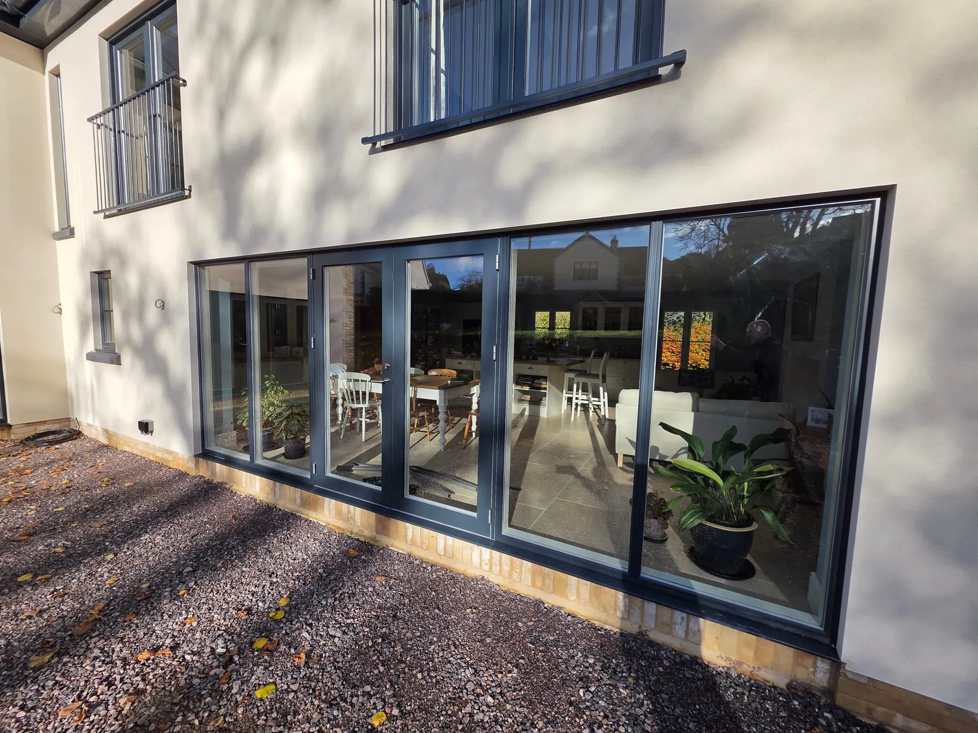 Full-width grey aluminium sliding doors across the back of a house