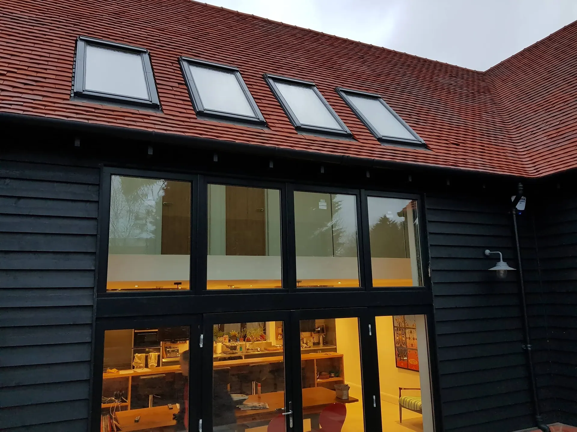 Full-height glazed doors and roof lights in a black timber-clad extension