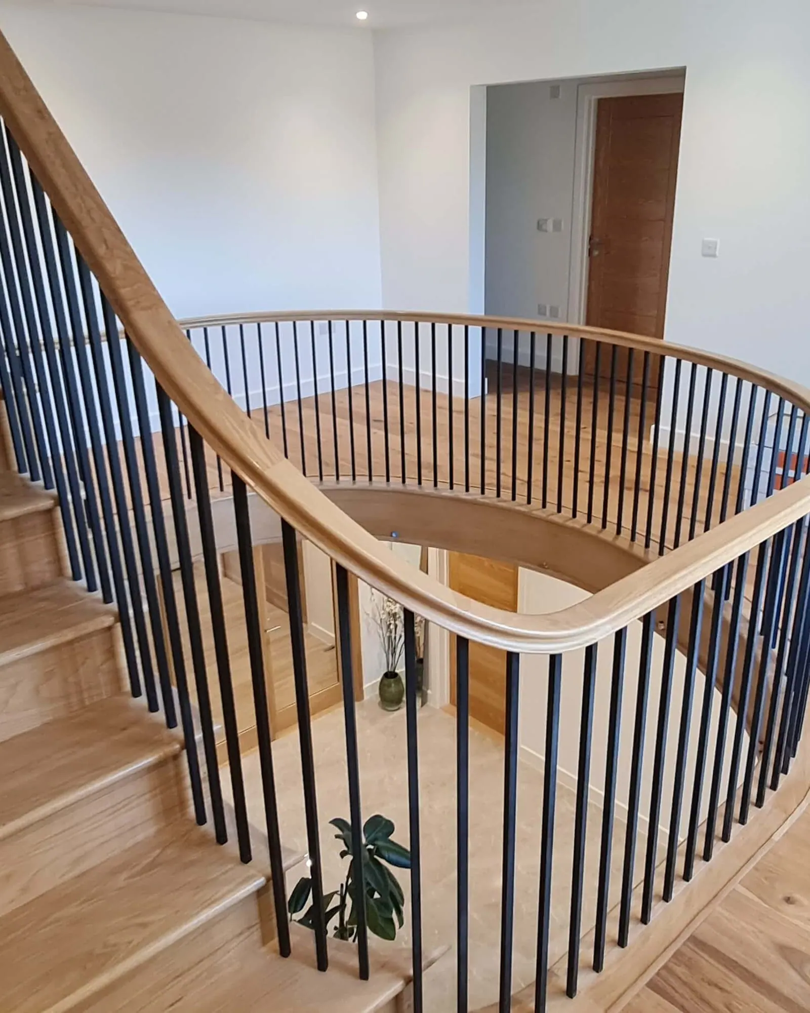 Oak staircase with a curved landing balustrade and black spindles